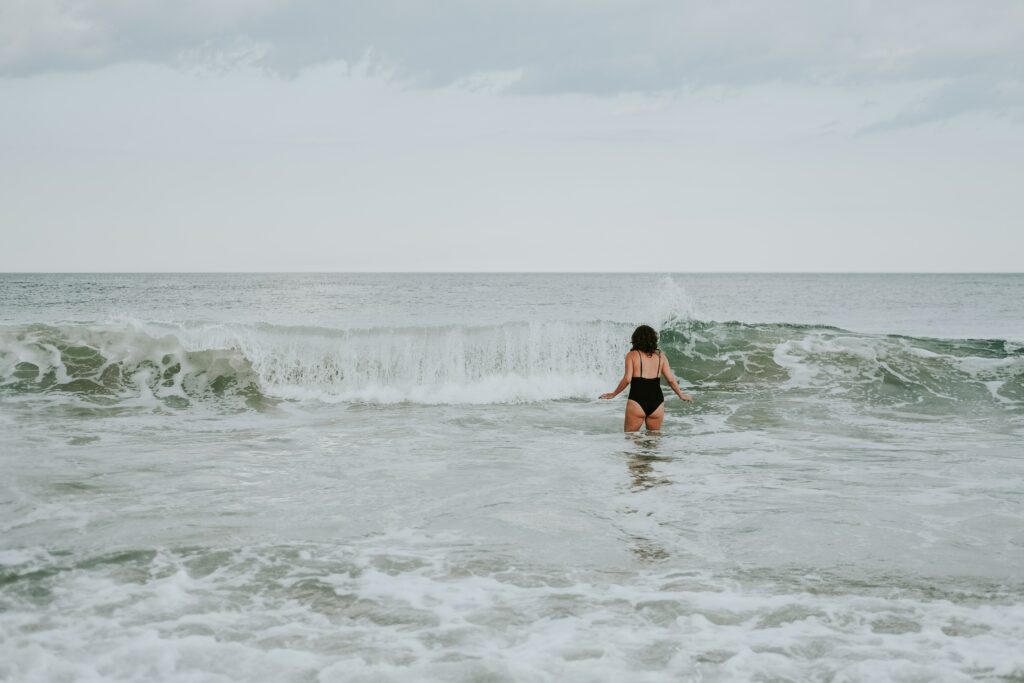 A women going for her morning swim. She is bracing for a wave that is rolling towards her.